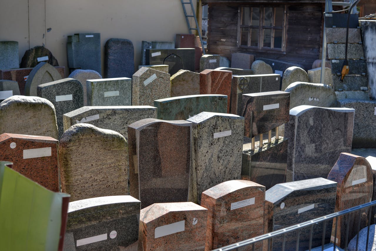 Diverse gravestones on display outdoors, showcasing different designs and materials ready for selection.